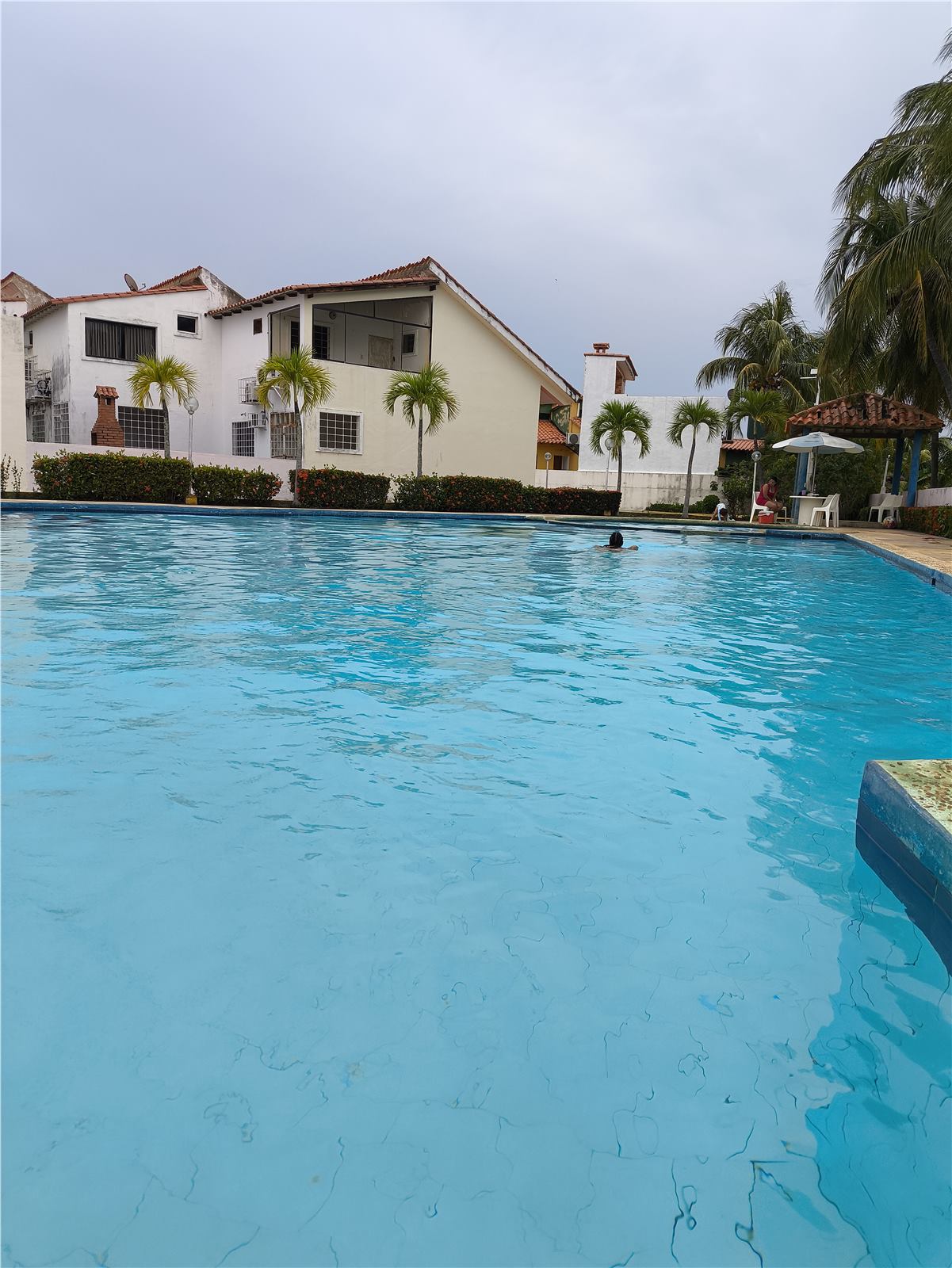 Piscina principal frente al townhouse con palmeras y área social