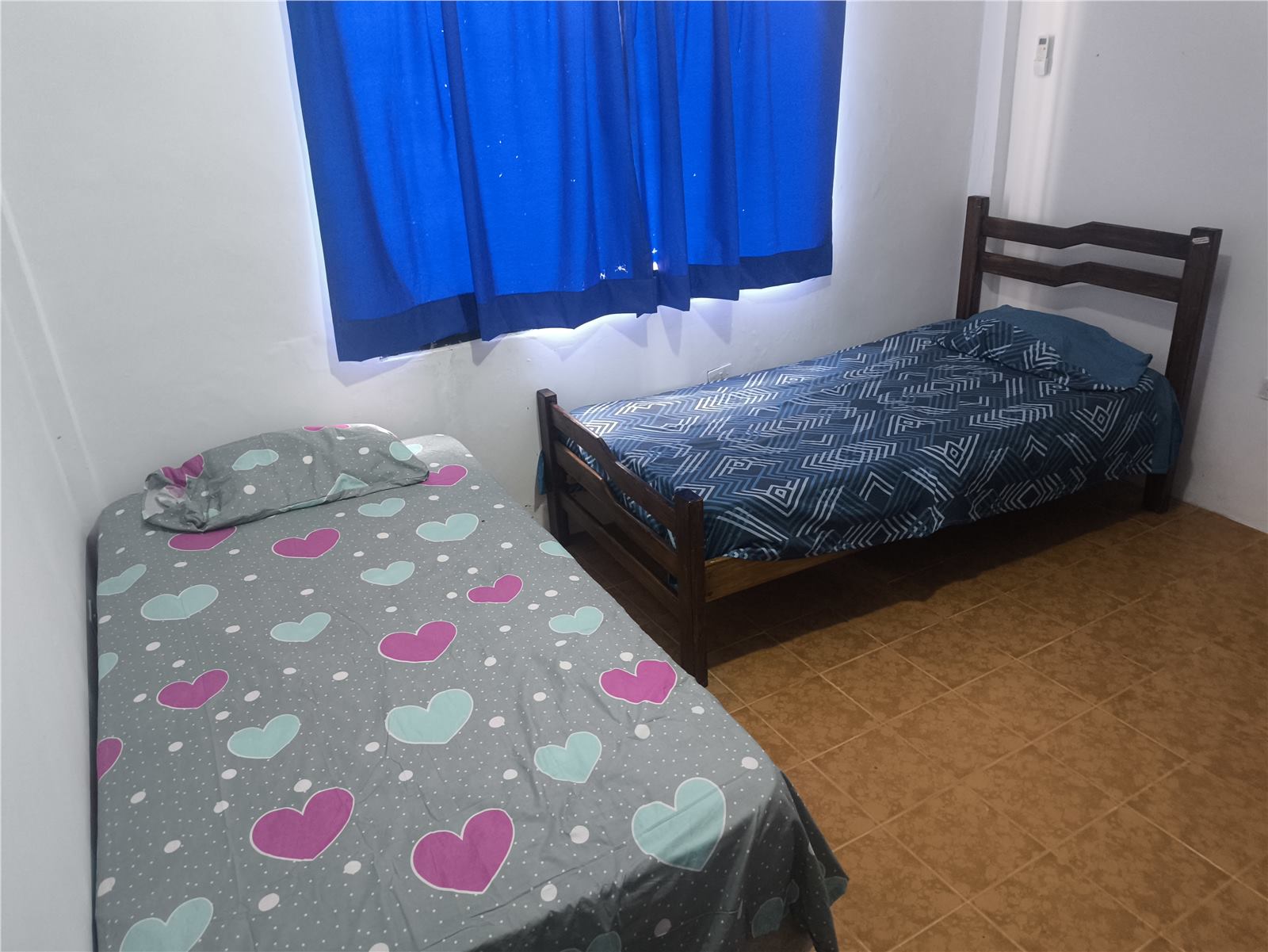 Habitación del townhouse con dos camas y ventana con cortina azul