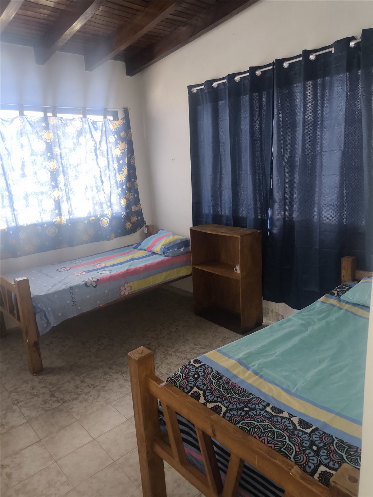 Habitación interior con camas individuales y cortinas oscuras